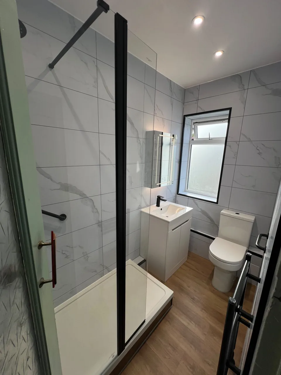 Narrow shower room with black fittings and wood-effect floor