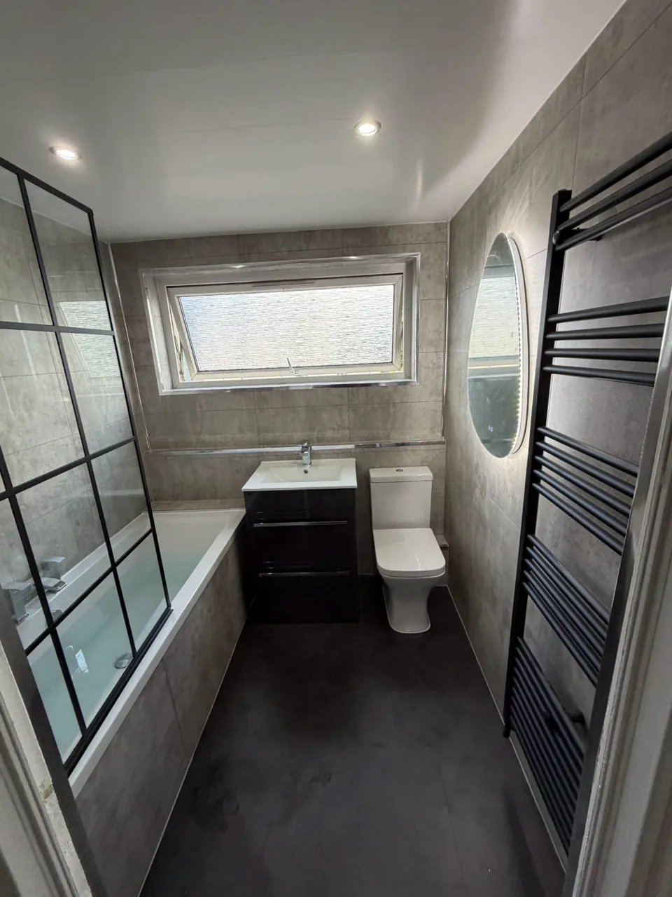 Fitted bath with black shower screen and dark vanity