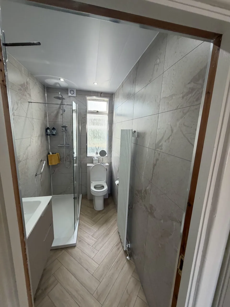 Narrow marble-effect shower room with white bathroom furniture